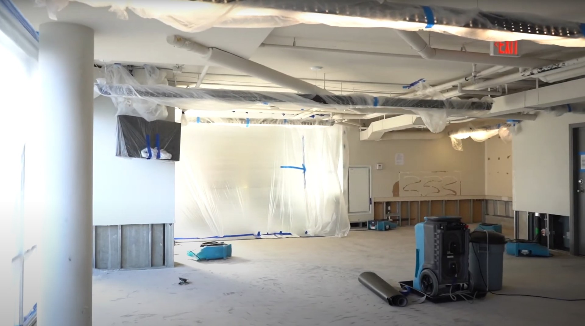 Professional commercial water damage restoration setup Commercial water damage restoration in progress with professional drying equipment and plastic sheeting